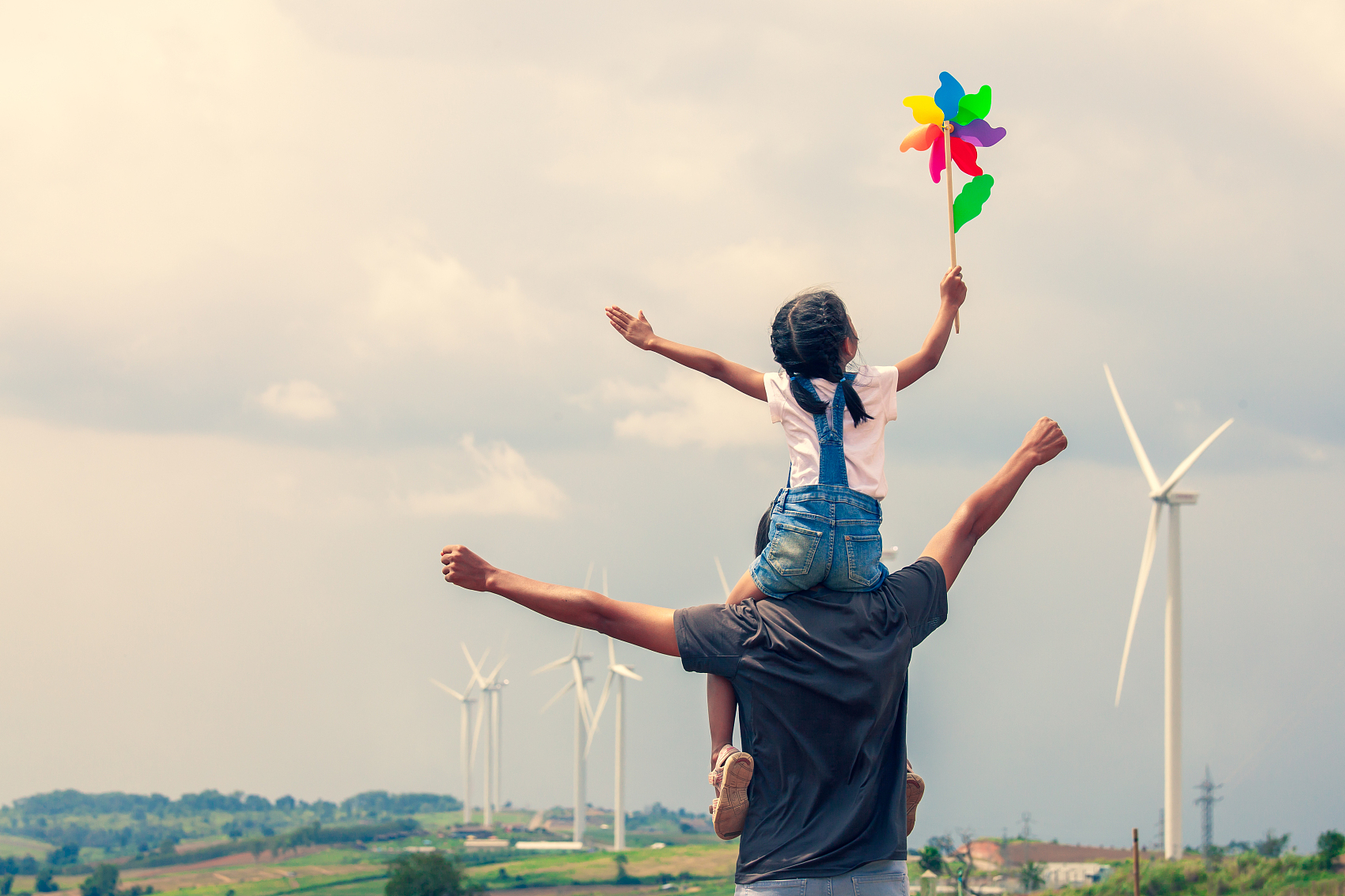 后视图的女儿与风车玩具坐在父亲的肩膀上，在背景风车.jpg